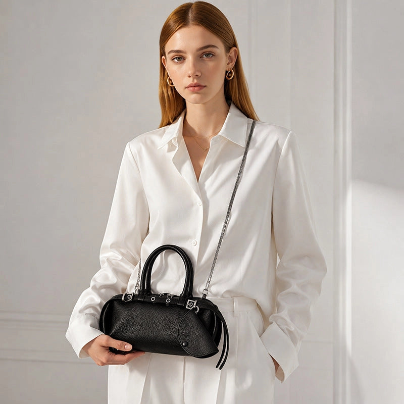 Woman wearing a black leather east-west satchel with a chain shoulder strap