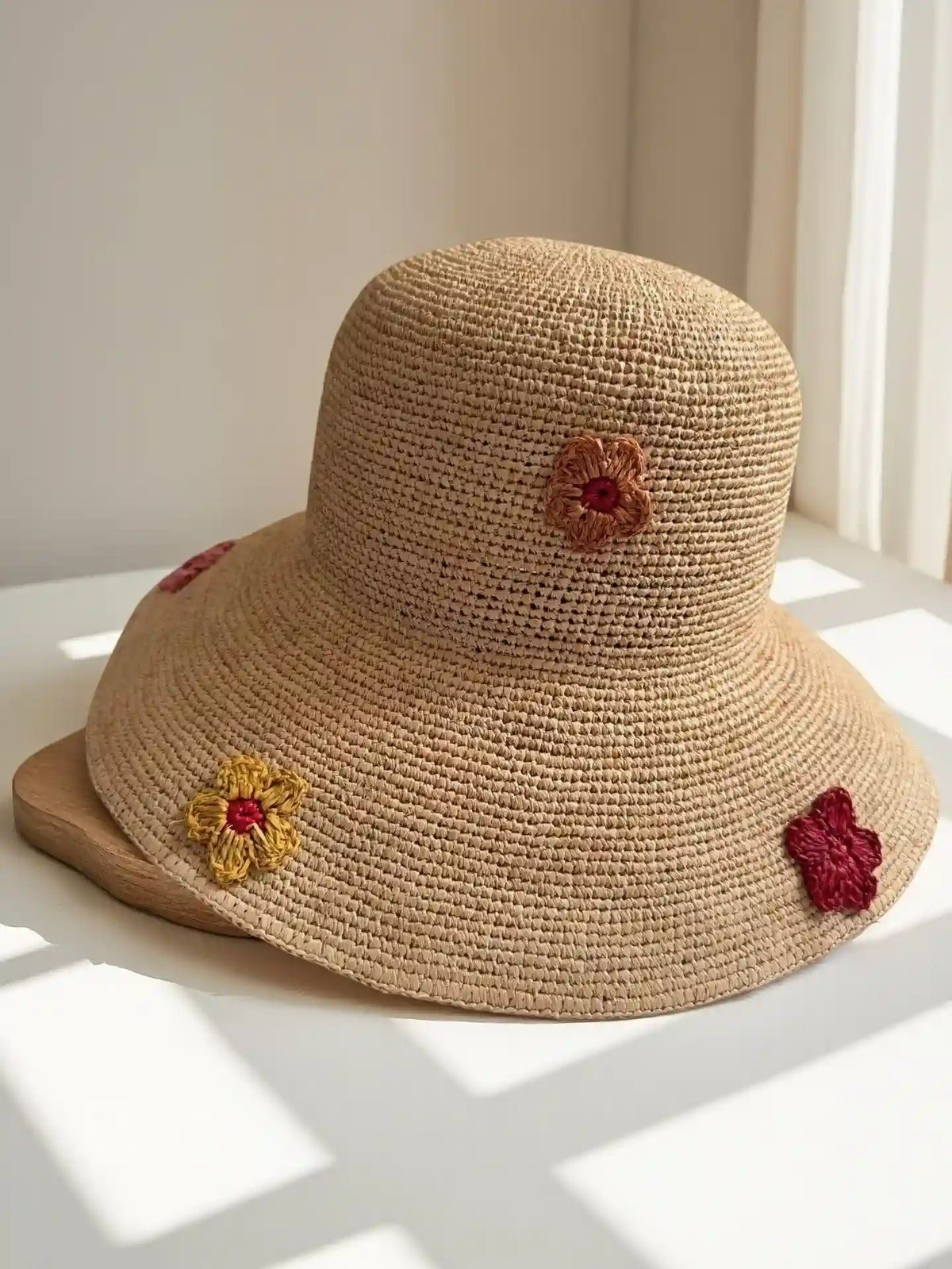 Natural beige handwoven raffia bucket hat with crochet flower appliqué in red and yellow, artisan sun hat for summer vacation styling