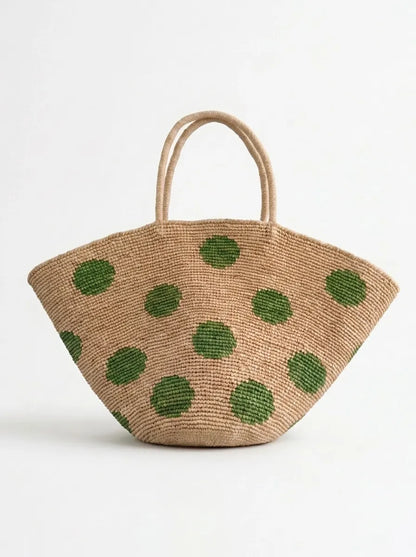 Natural beige handwoven raffia fan tote bag with green polka dot pattern, playful crochet straw beach bag on white background