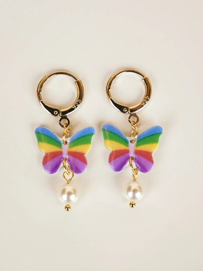 Rainbow butterfly charm hoop earrings with pearl drop and gold huggie hoops on white background