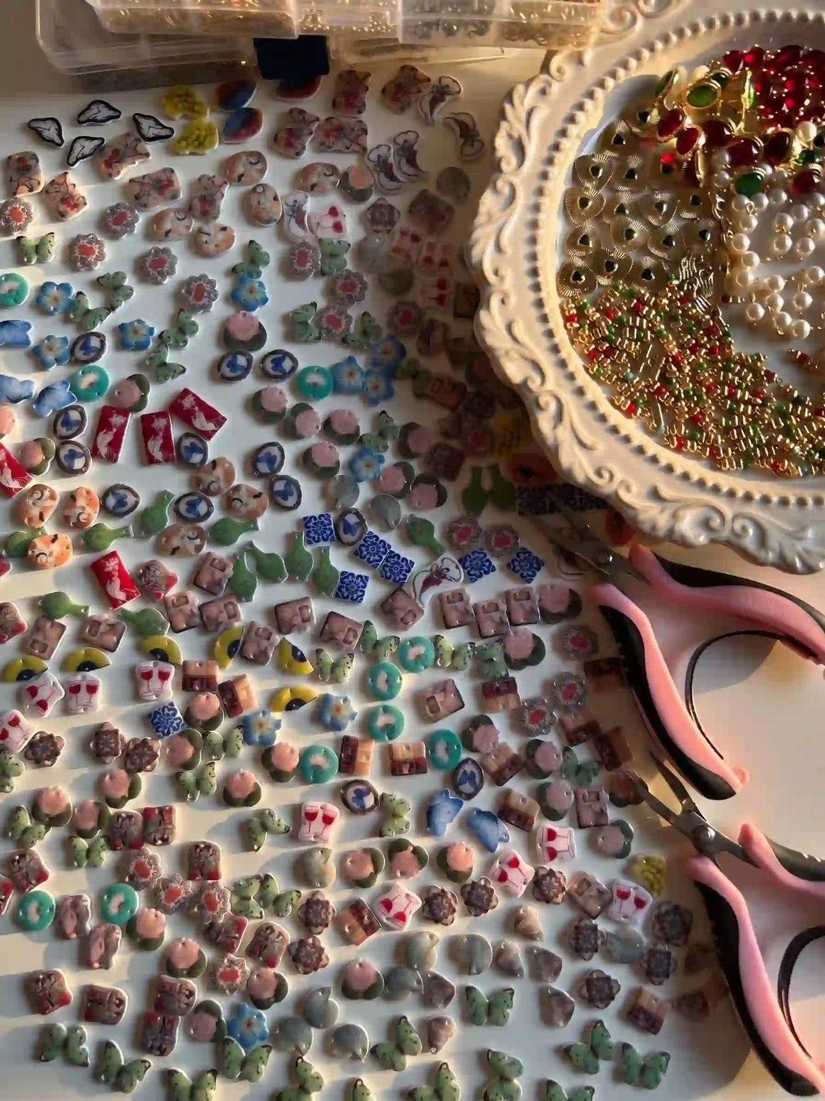 Handmade charm earring making process with colorful miniature resin and ceramic charms spread on studio table, artisan jewelry craftsmanship behind the scenes