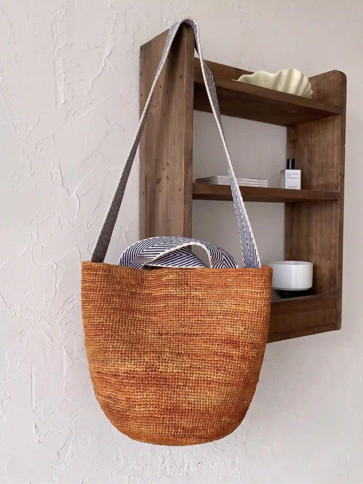 Rust orange handwoven raffia shoulder bag with striped canvas long strap, minimalist everyday eco bag styled in neutral home interior