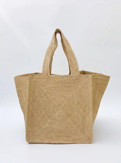 Large handwoven raffia tote bag with geometric spiral weave pattern and structured silhouette on white background