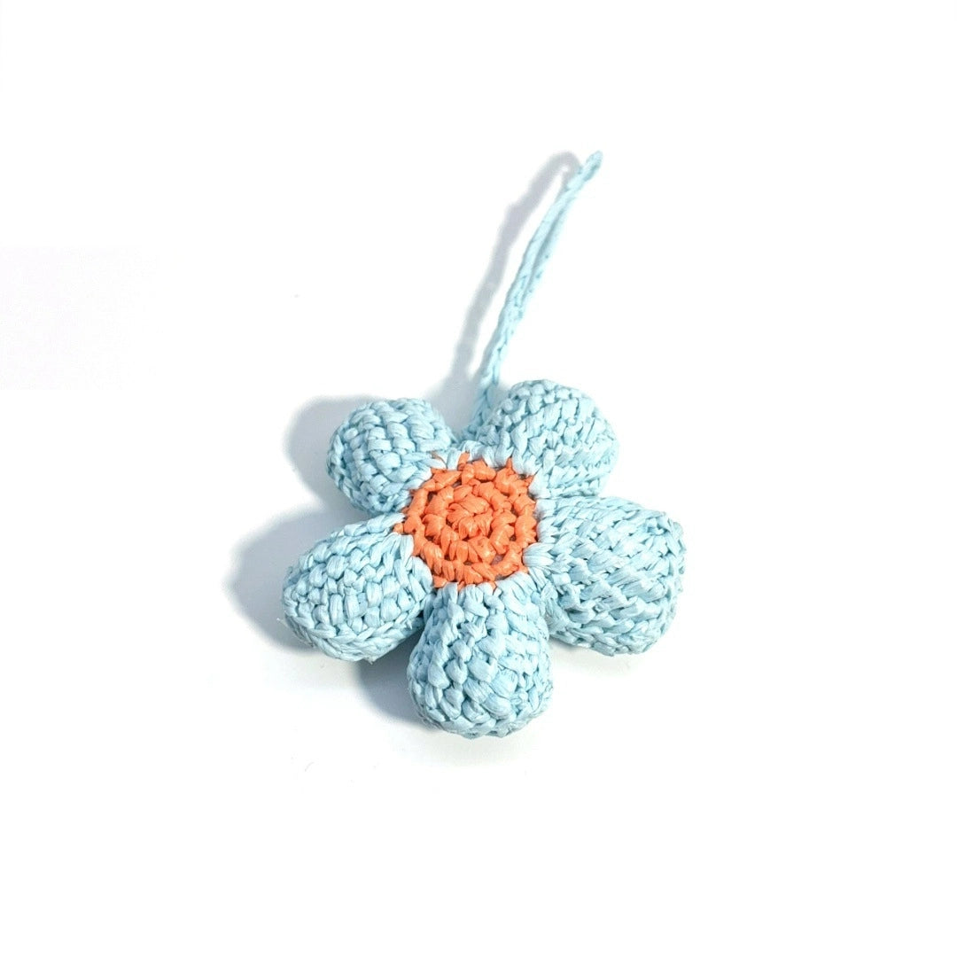 Light blue hand-crocheted raffia flower bag charm with five rounded petals and an orange center on a white background.