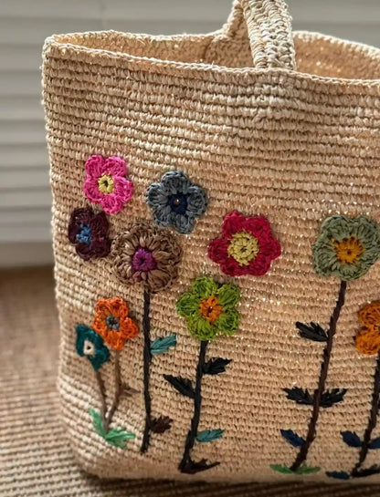 Close-up floral embroidery detail on handwoven raffia bag – sustainable artisan craftsmanship