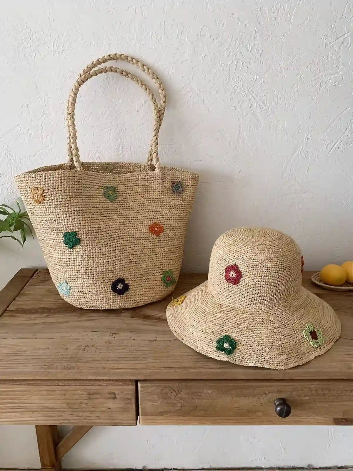 Matching handwoven raffia tote bag and bucket hat set with colorful flower embroidery, French countryside boho summer accessories on vintage wooden table