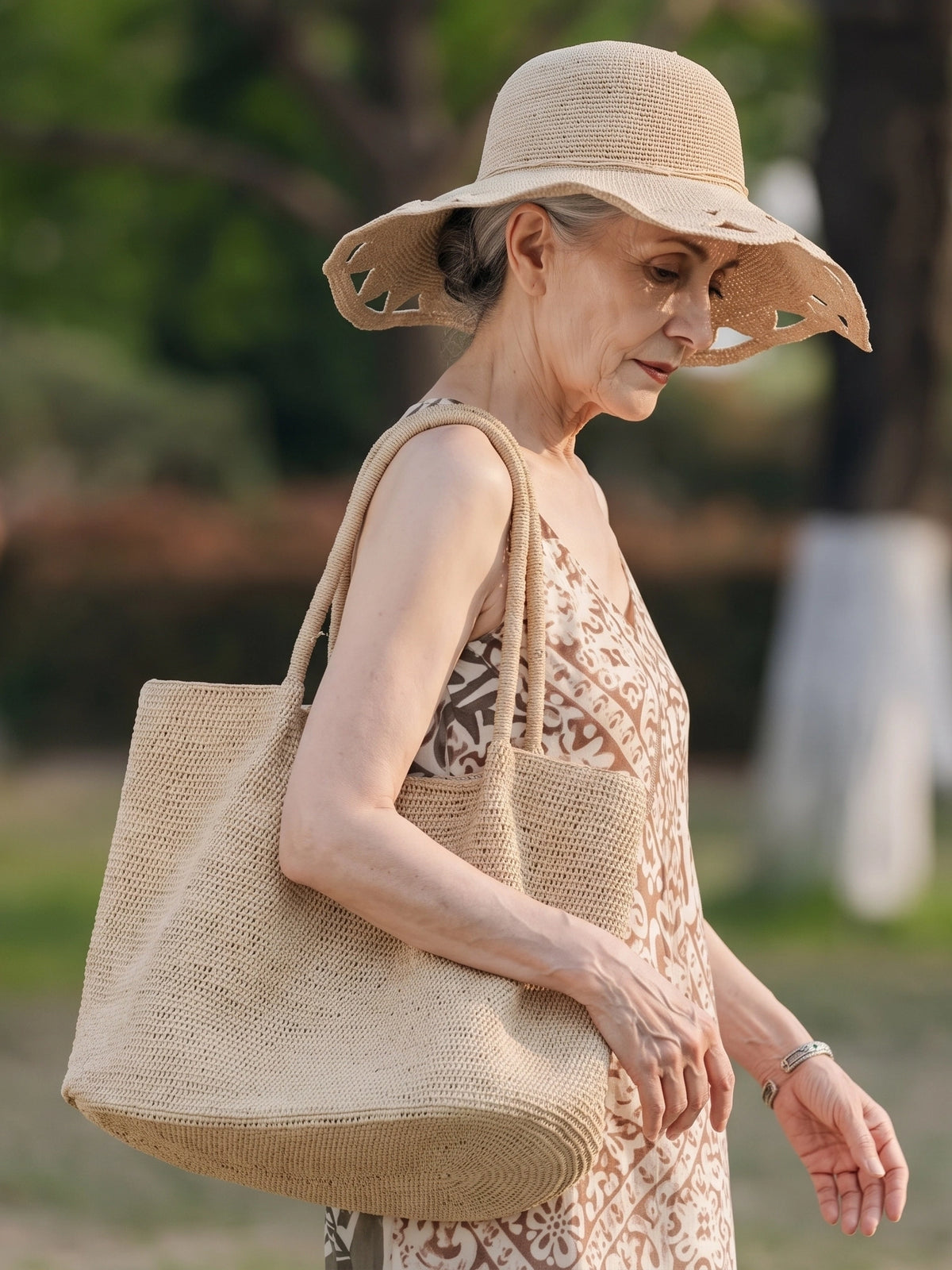 Large natural raffia tote bag styled with linen dress and woven sun hat for a slow summer outdoor look