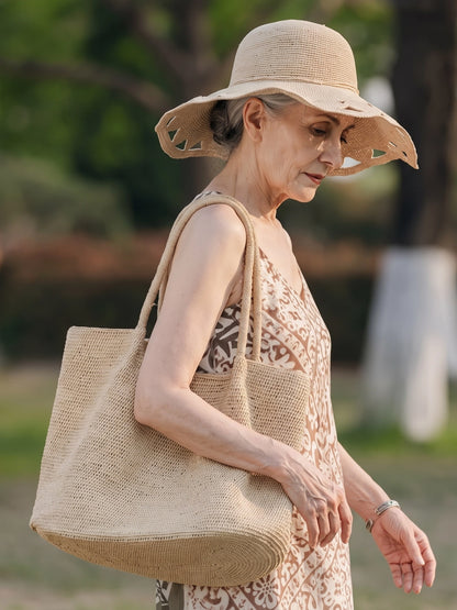 Large natural raffia tote bag styled with linen dress and woven sun hat for a slow summer outdoor look