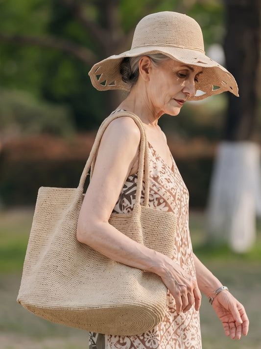 Large natural raffia tote bag styled with linen dress and woven sun hat for a slow summer outdoor look